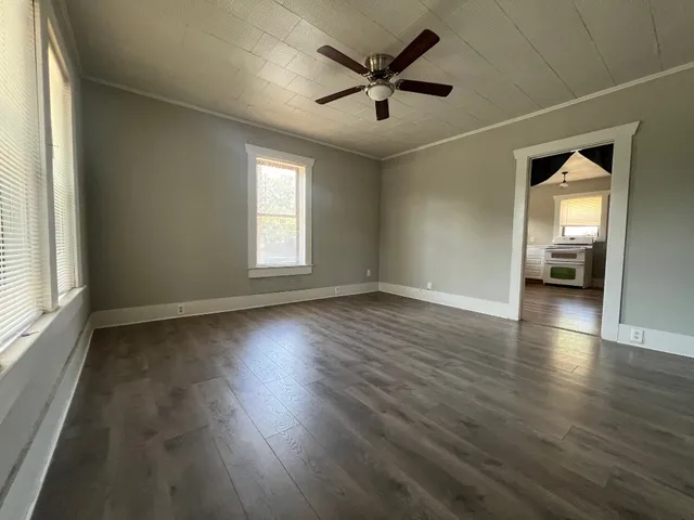 an empty room with wooden floor and windows