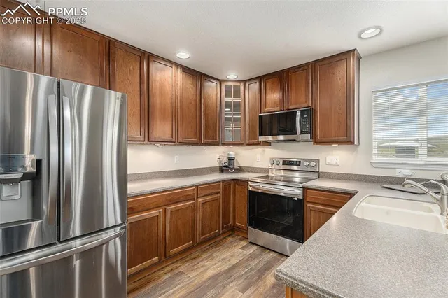 a kitchen with granite countertop stainless steel appliances cabinets a sink and a window