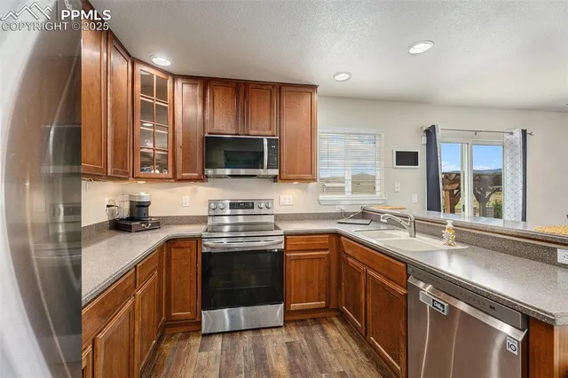 a kitchen with stainless steel appliances granite countertop wooden cabinets a sink and dishwasher a stove top oven with wooden floor
