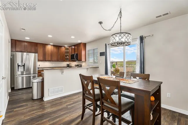 a view of a dining room with furniture large window a chandelier and kitchen view
