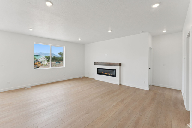 1004 West Paramount Cove South, Unit 315 Ogden, UT 84405 - Photo 6 of 42 Open-concept living space featuring wood-finish flooring, recessed lighting, and a modern linear fireplace with a stained wood mantel