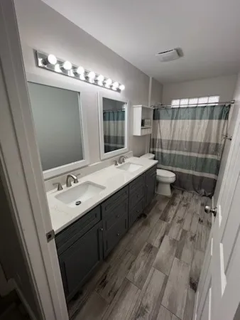 a bathroom with a double vanity sink a large mirror and a shower