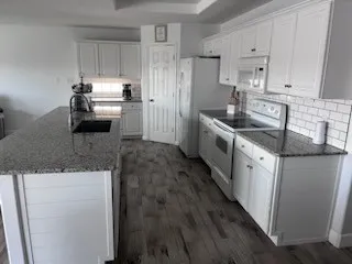 a kitchen with granite countertop a sink stove and refrigerator