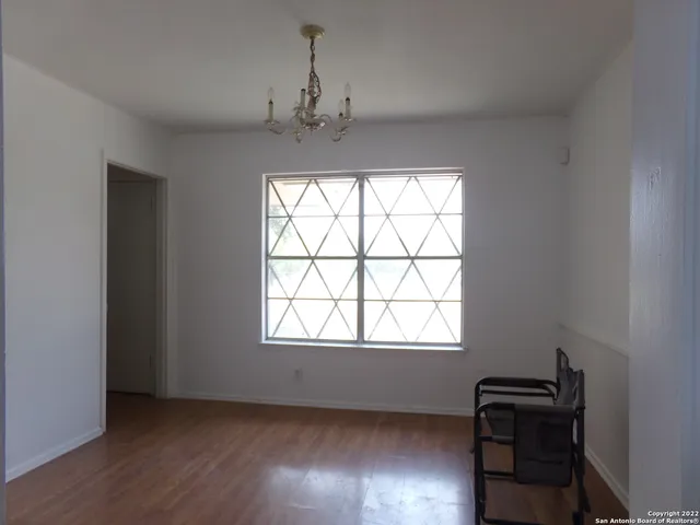 a view of a hallway with wooden floor and a cabinet
