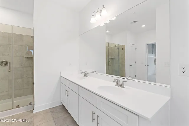 a bathroom with a double vanity sink a shower and a mirror