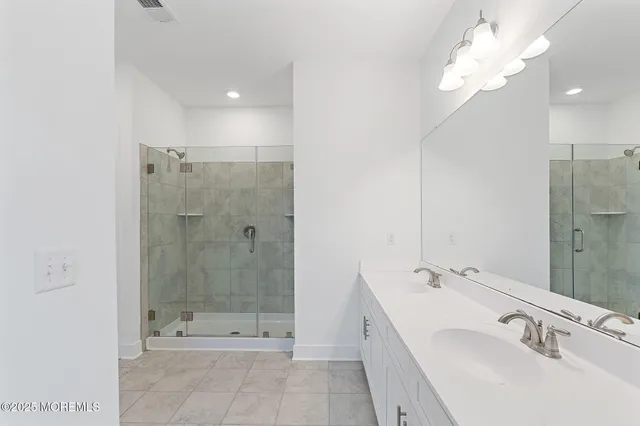 a bathroom with a double vanity sink mirror and shower