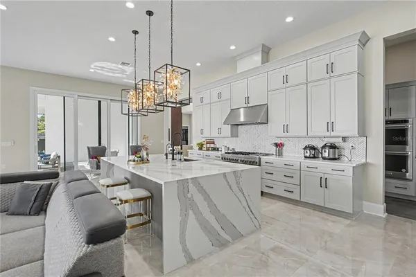 a large kitchen with kitchen island a chandelier stainless steel appliances a stove a sink dishwasher and a chandelier