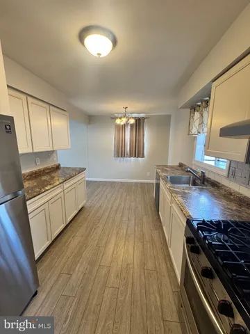 a kitchen with granite countertop wooden floors a stove and a sink