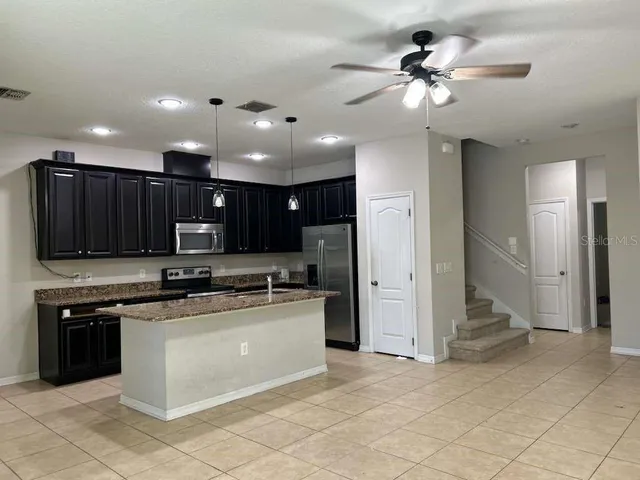 a kitchen with stainless steel appliances granite countertop a stove top oven a sink and a refrigerator