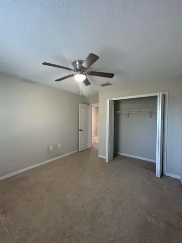 a view of an empty room with a chandelier fan