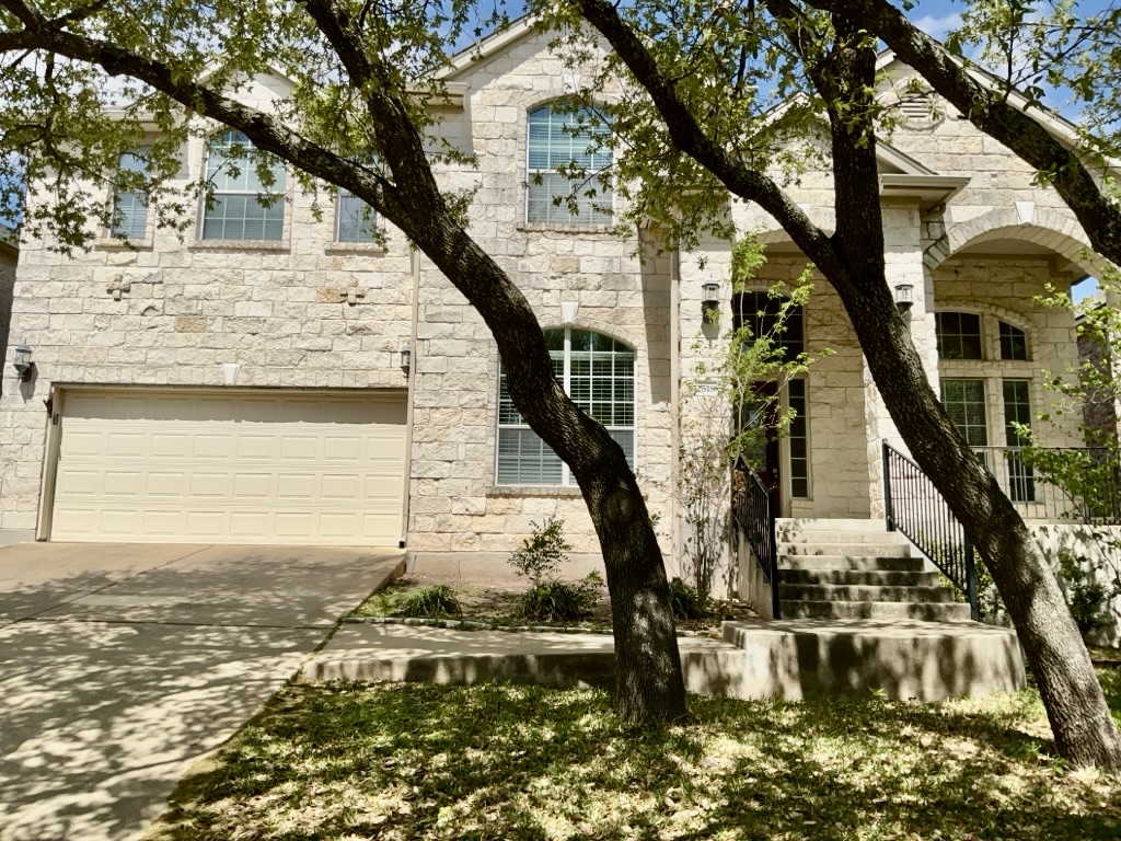 View of front of house featuring stone siding, an attached garage, and driveway