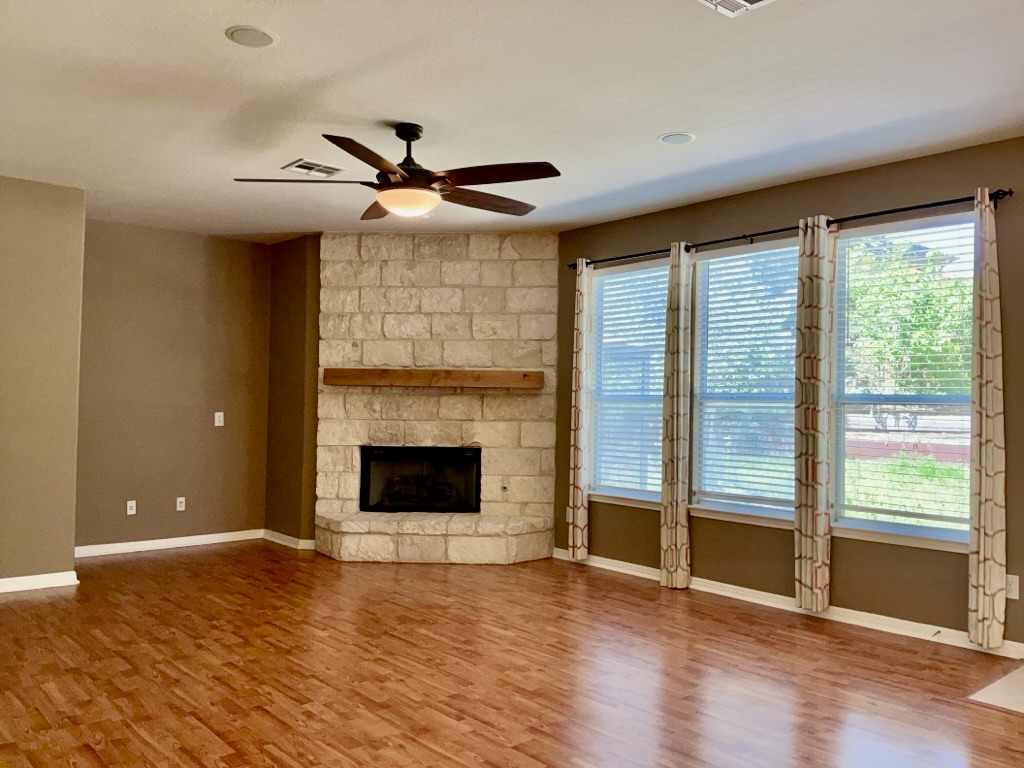 2518 Vestavia Ridge Lane Cedar Park, TX 78613 - Photo 2 of 23 living room featuring wood finished floors, a ceiling fan, and a fireplace