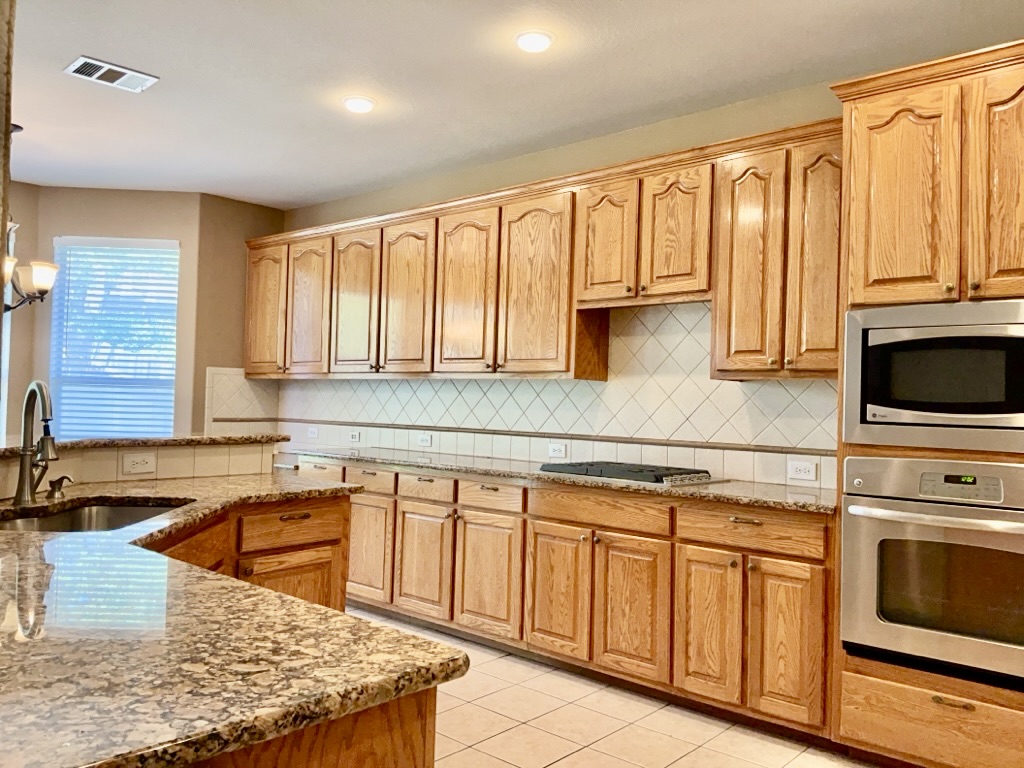 2518 Vestavia Ridge Lane Cedar Park, TX 78613 - Photo 4 of 23 Kitchen with light stone countertops, stainless steel appliances, light tile patterned flooring, pendant lighting, and backsplash