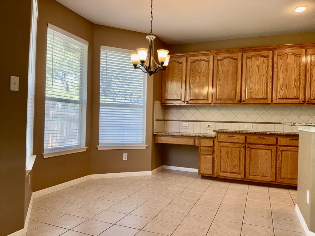 2518 Vestavia Ridge Lane Cedar Park, TX 78613 - Photo 6 of 23 Kitchen with wood finish cabinetry, light tile patterned floors, a chandelier, backsplash, and light stone counters
