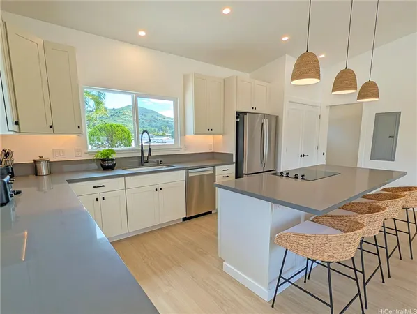 a kitchen with stainless steel appliances granite countertop a sink a stove a refrigerator cabinets and chairs