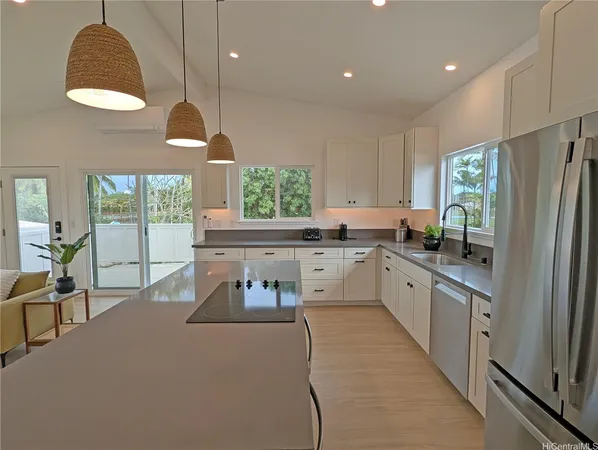 a kitchen with stainless steel appliances granite countertop a refrigerator a sink dishwasher a stove and a dining table with wooden floor