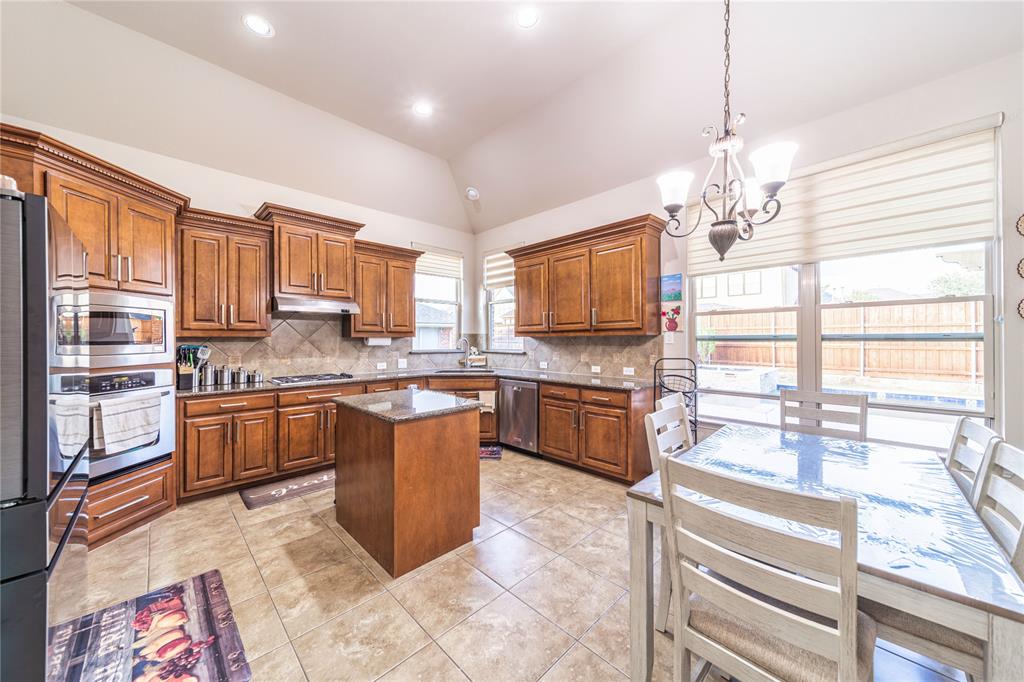 720 Nighthawk Drive Murphy, TX 75094 - Photo 13 of 40 a kitchen with stainless steel appliances granite countertop a stove top oven a sink dishwasher a dining table and chairs with wooden floor