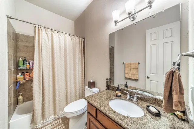 a bathroom with a granite countertop sink toilet and a mirror