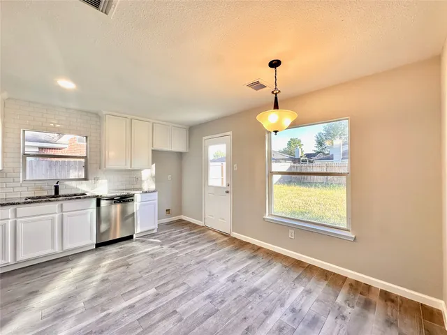 a kitchen with stainless steel appliances granite countertop a stove top oven a sink dishwasher and a refrigerator with wooden floor