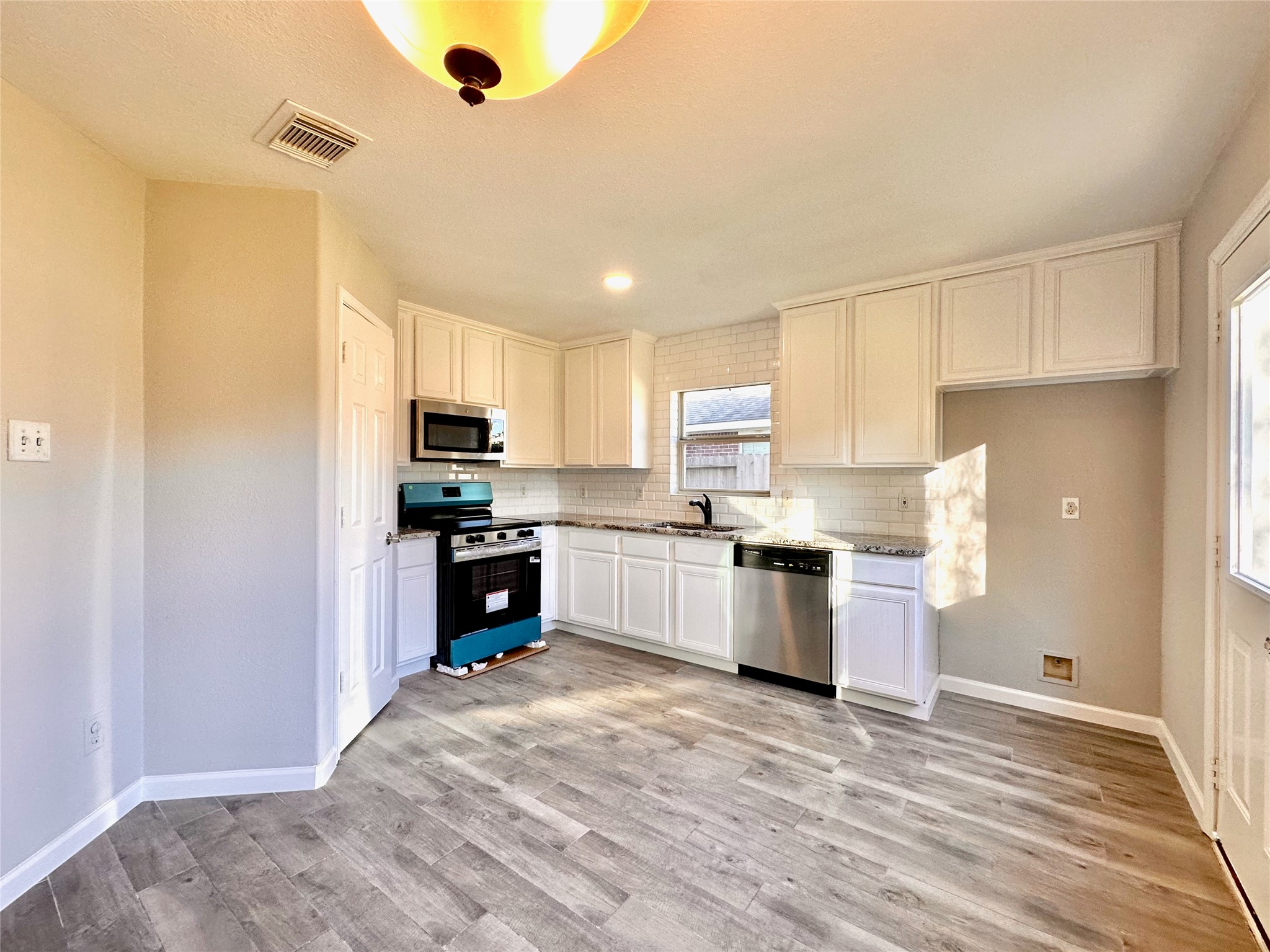 3042 Trinity Pass Court Spring, TX 77373 - Photo 14 of 34 a kitchen with granite countertop a refrigerator oven a sink dishwasher and white cabinets with wooden floor