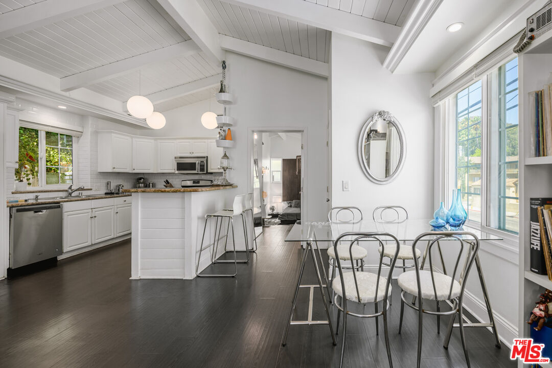 2225 North Cahuenga Boulevard Los Angeles, CA 90068 - Photo 12 of 30 a kitchen with stainless steel appliances granite countertop a stove top oven a sink a dining table and chairs with wooden floor