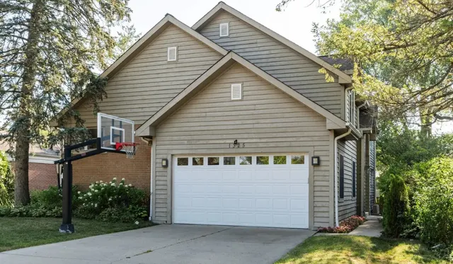 a view of a white house with a small yard and a large tree