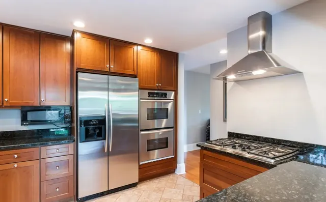 a kitchen with stainless steel appliances granite countertop a refrigerator and a stove