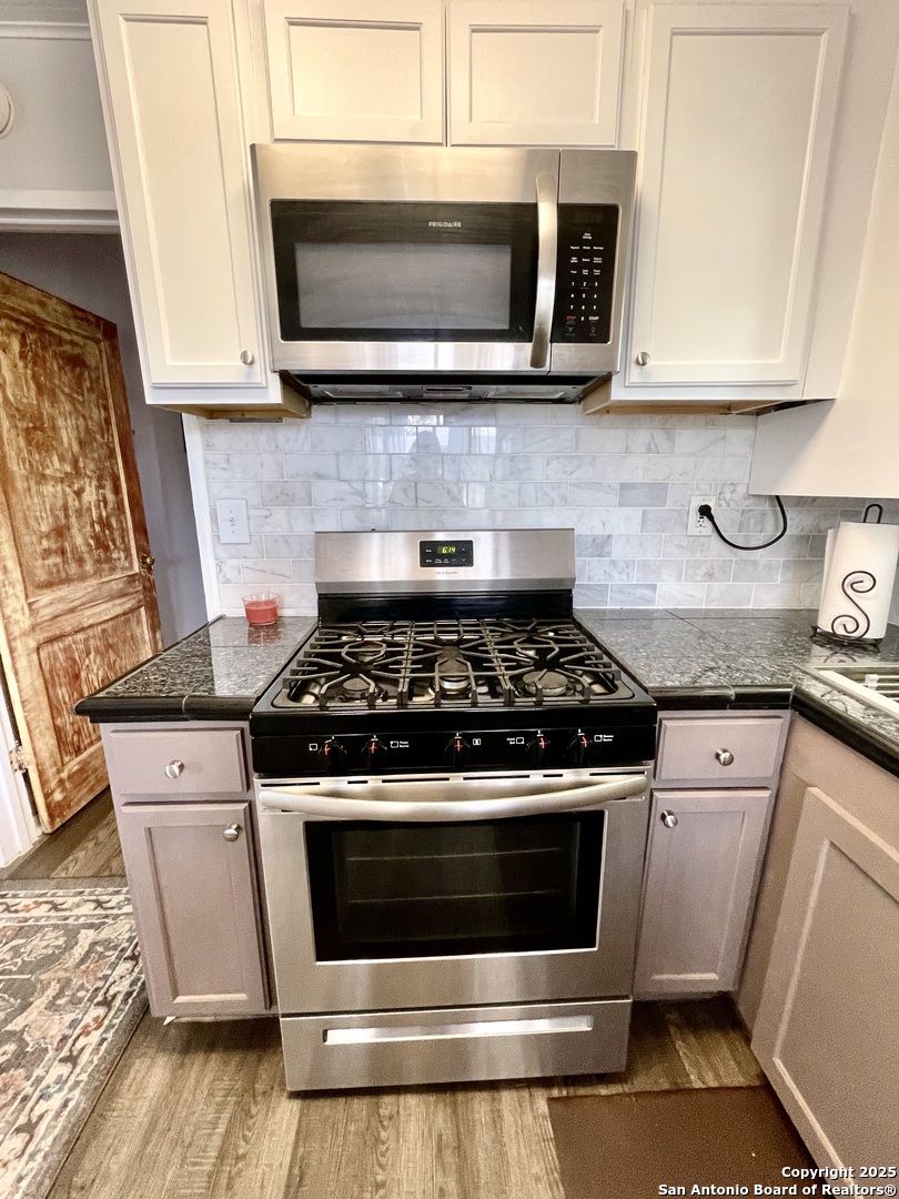 406 Hackberry Street Bandera, TX 78003 - Photo 16 of 34 a kitchen with granite countertop a stove and a microwave