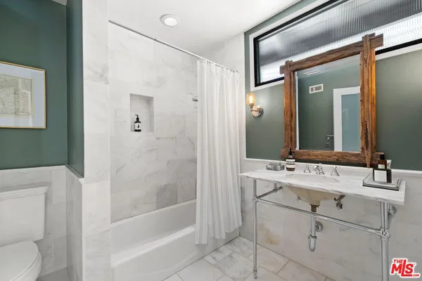 a bathroom with a bathtub shower sink vanity and toilet