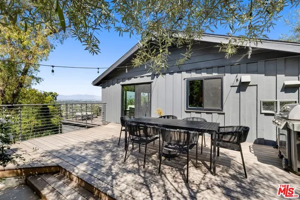 a view of a patio with table and chairs with wooden floor and fence