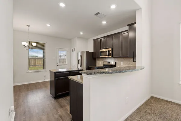a kitchen with kitchen island a counter top space stainless steel appliances and cabinets