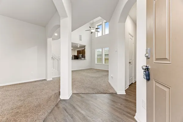 an empty room with wooden floor and a kitchen