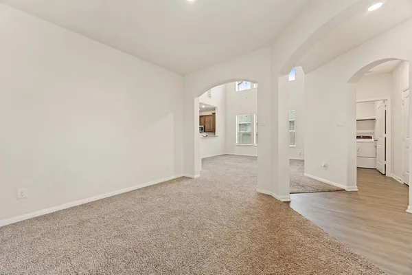 a view of an empty room with kitchen and a window