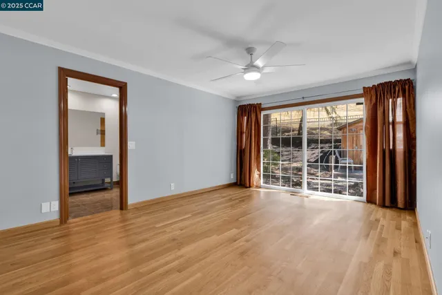 a view of an empty room with wooden floor and a window