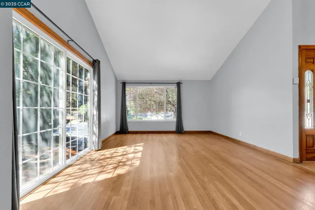 a view of an empty room with a window and wooden floor