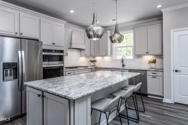 a kitchen with stainless steel appliances granite countertop a sink a stove a refrigerator and island