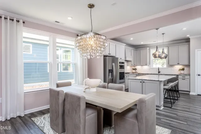 a kitchen with stainless steel appliances a dining table chairs and wooden floor