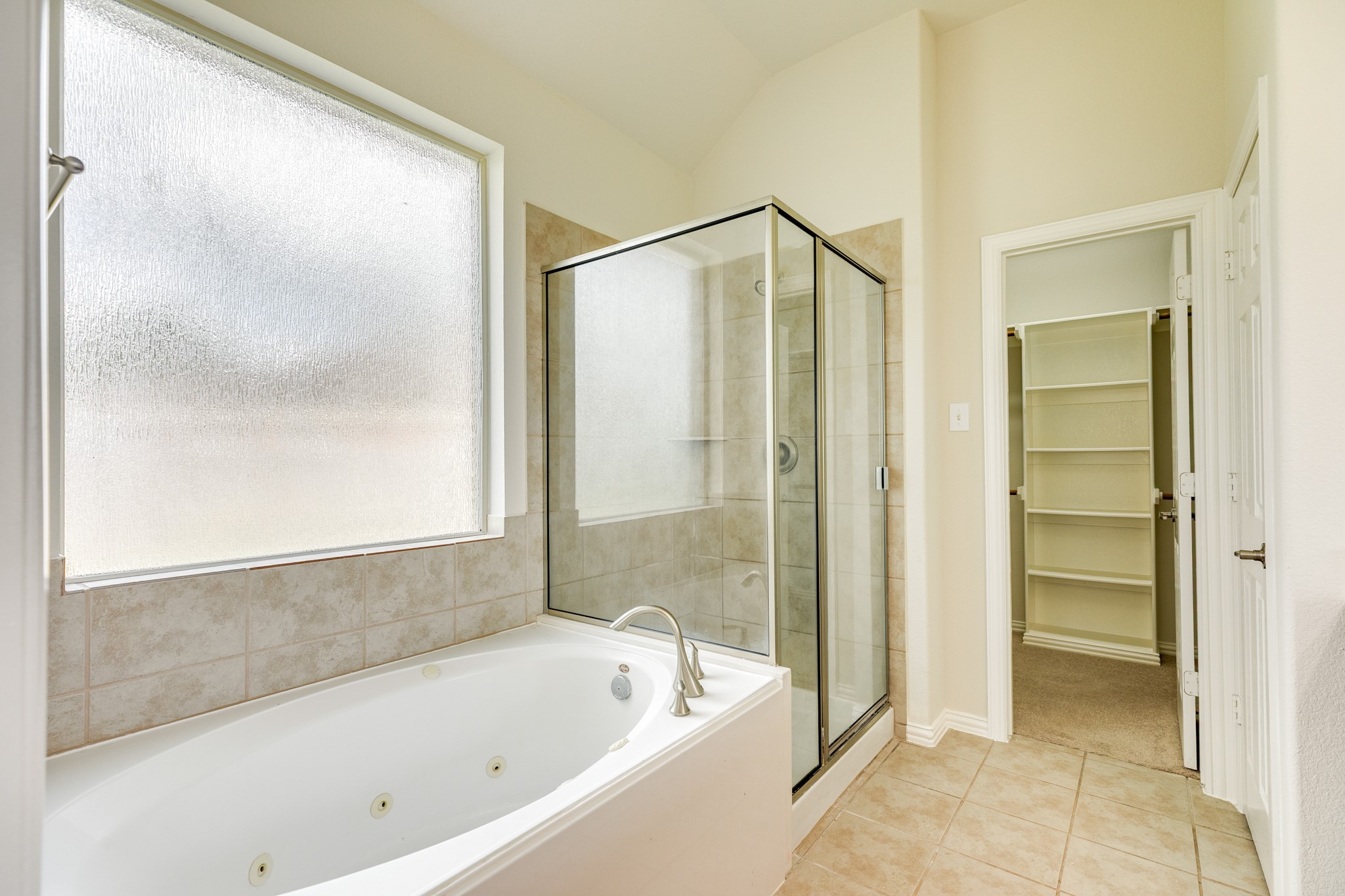 13417 Star Creek Lane Rosharon, TX 77583 - Photo 21 of 41 This view showcases the frosted window above the soaking tub, the glass shower, the walk-in closet, and the tile flooring.