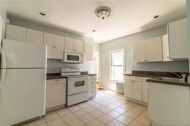 a kitchen with white cabinets and white appliances