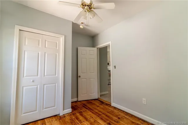 an empty room with wooden floor closet and windows