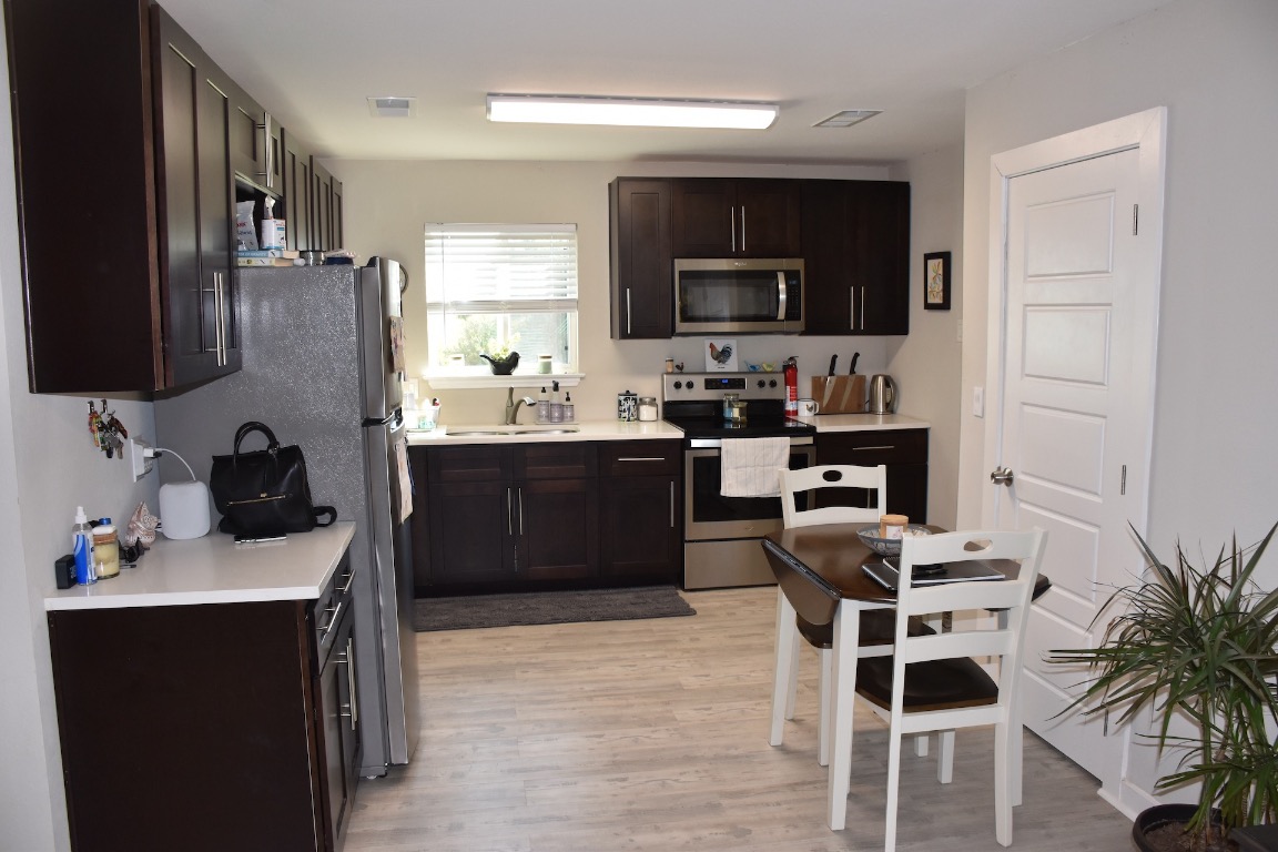 3775 County Road 463 Elgin, TX 78621 - Photo 9 of 28 Kitchen featuring dark brown cabinetry, appliances with stainless steel finishes, light countertops, and light wood-style flooring