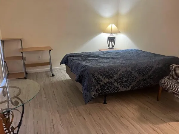 a bedroom with a bed wooden floor and lamp