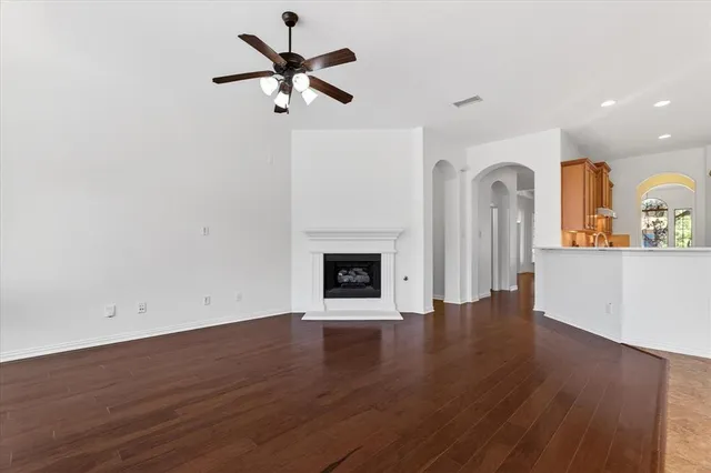 a view of a room with wooden floor a ceiling fan a fireplace and windows
