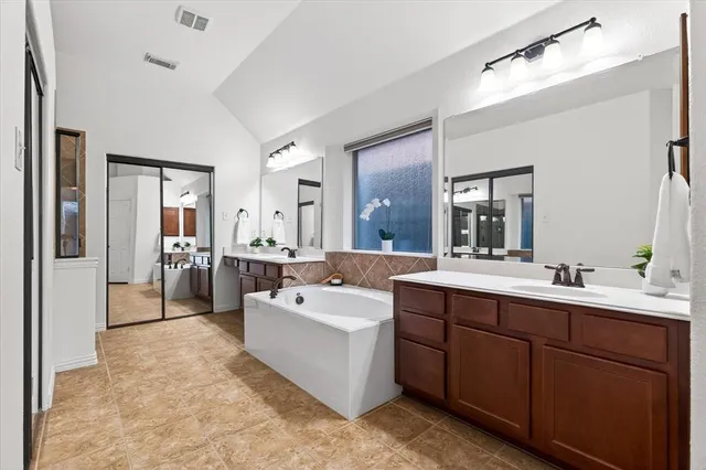 a spacious bathroom with a tub sink and mirror