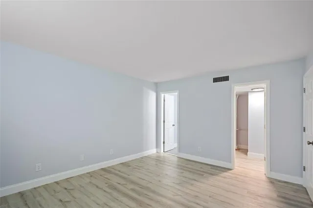 a view of an empty room with wooden floor and closet