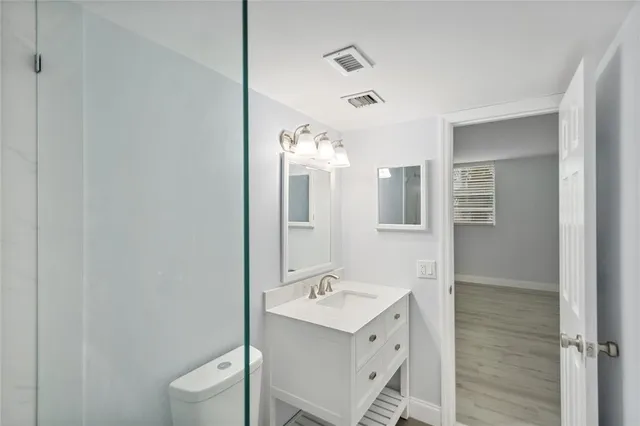a bathroom with a sink a toilet a mirror and shower