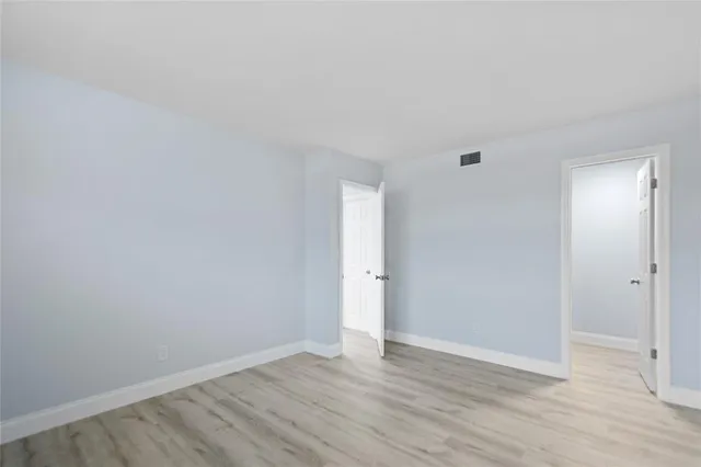a view of an empty room with wooden floor and closet