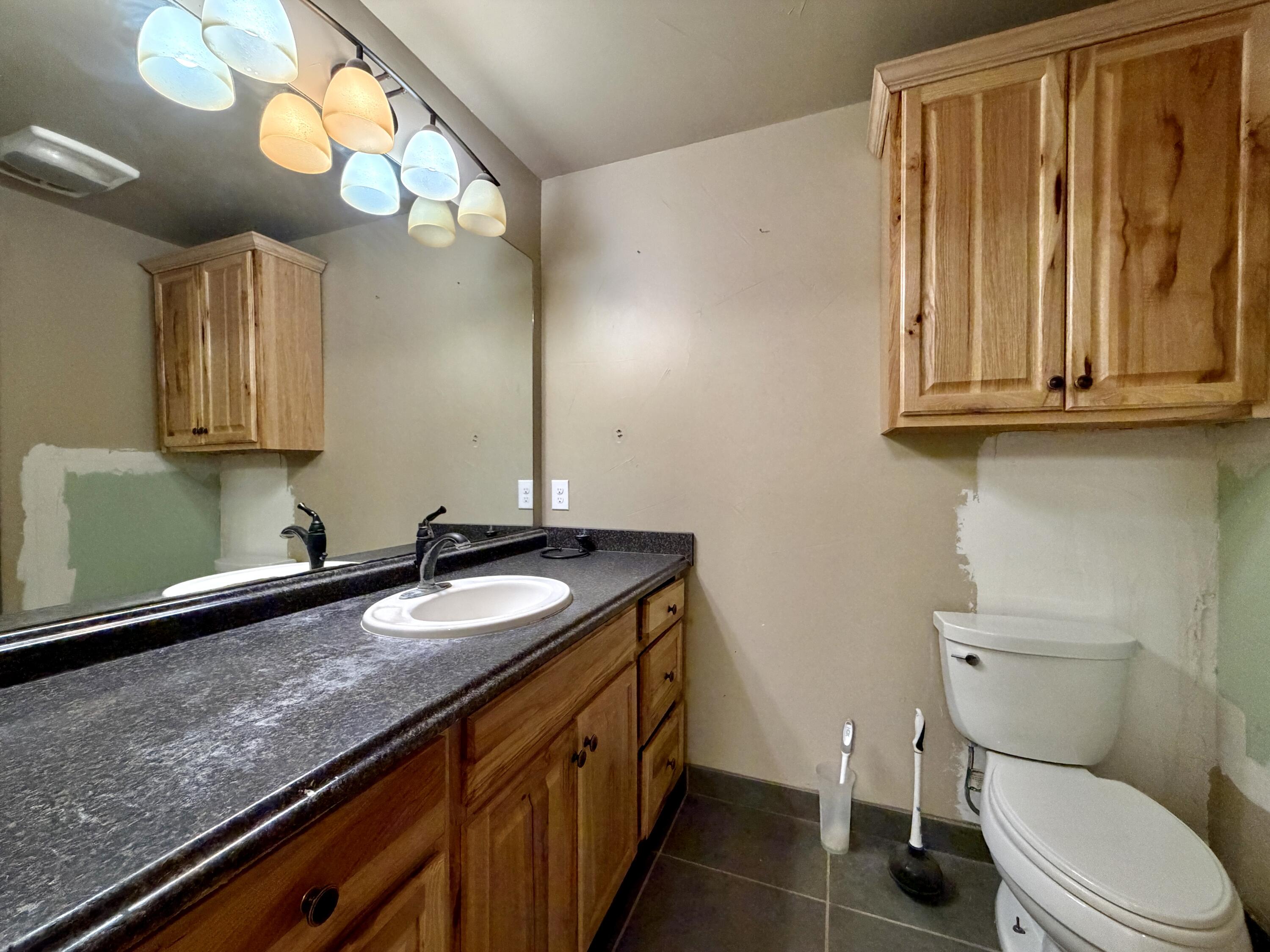4401 28th Street Lubbock, TX 79410 - Photo 23 of 25 a bathroom with a granite countertop sink and a toilet