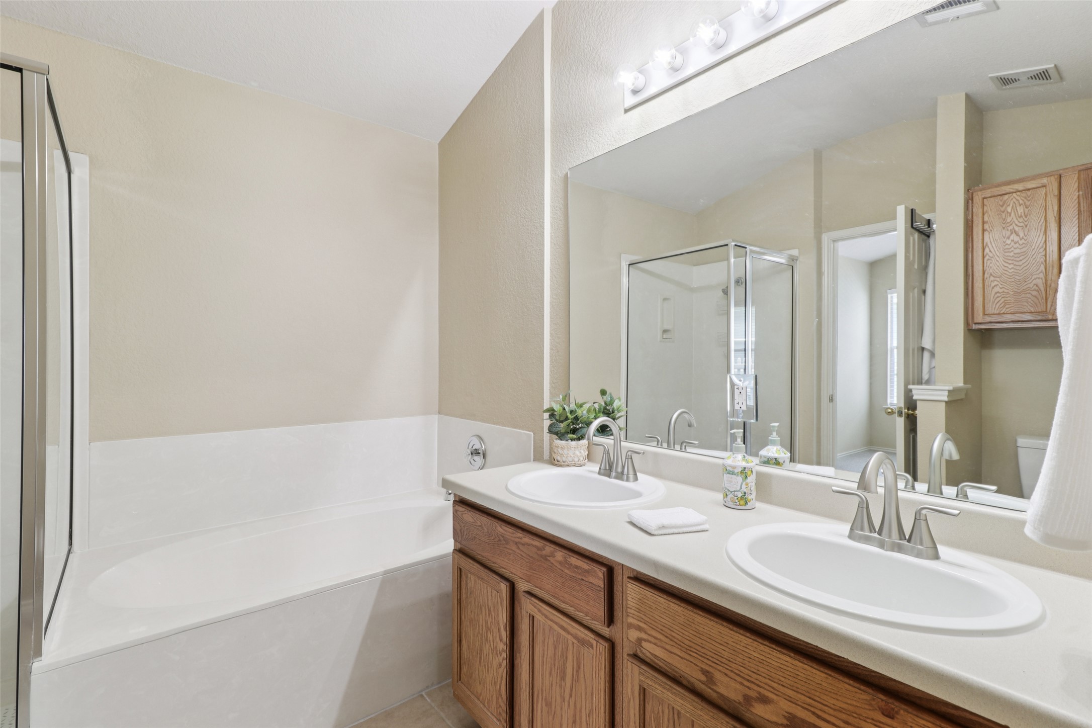 700 Scheel Road Kyle, TX 78640 - Photo 25 of 39 The property features a bathroom with a double vanity, a built-in bathtub, and a separate glass-enclosed shower