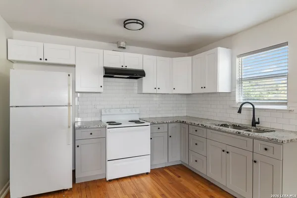 a kitchen with cabinets appliances a sink and a window
